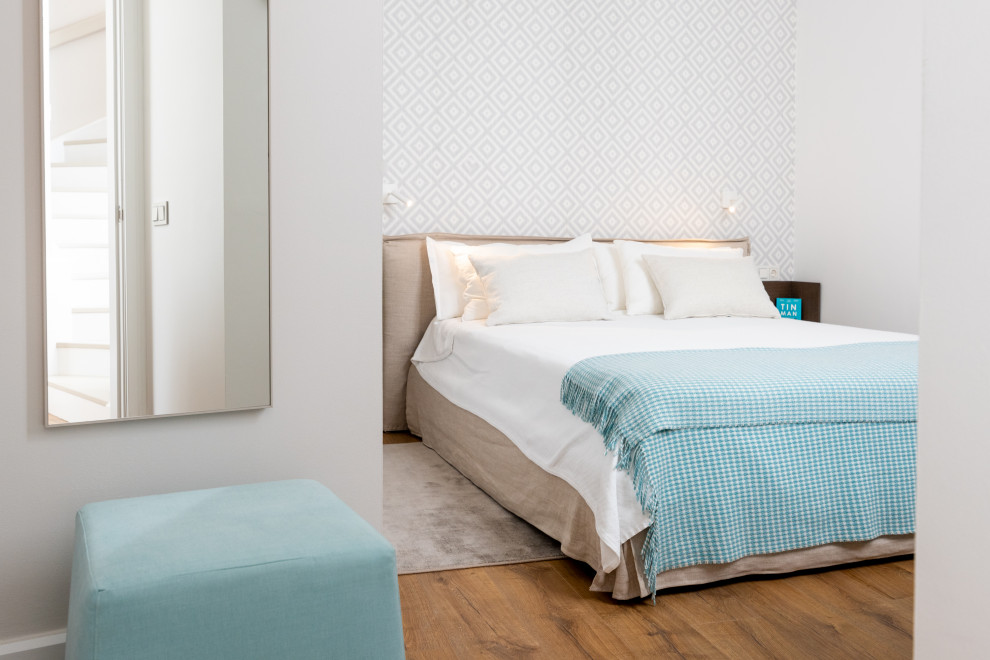 Immagine di una camera degli ospiti design di medie dimensioni con pareti bianche, pavimento in legno massello medio, pavimento marrone e carta da parati