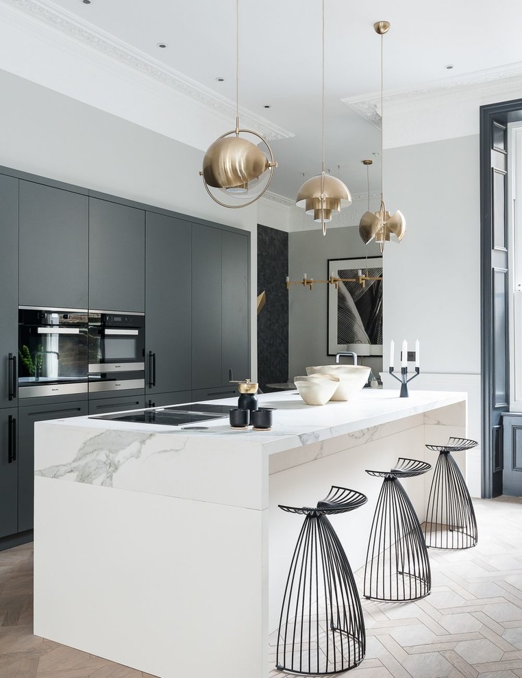 Inspiration for a contemporary galley kitchen in Cornwall with flat-panel cabinets, grey cabinets, light hardwood floors, with island, beige floor and white benchtop.