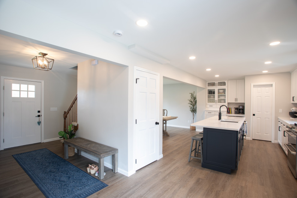 Example of a transitional vinyl floor kitchen design with shaker cabinets, white cabinets, quartz countertops, white backsplash, porcelain backsplash, stainless steel appliances and white countertops