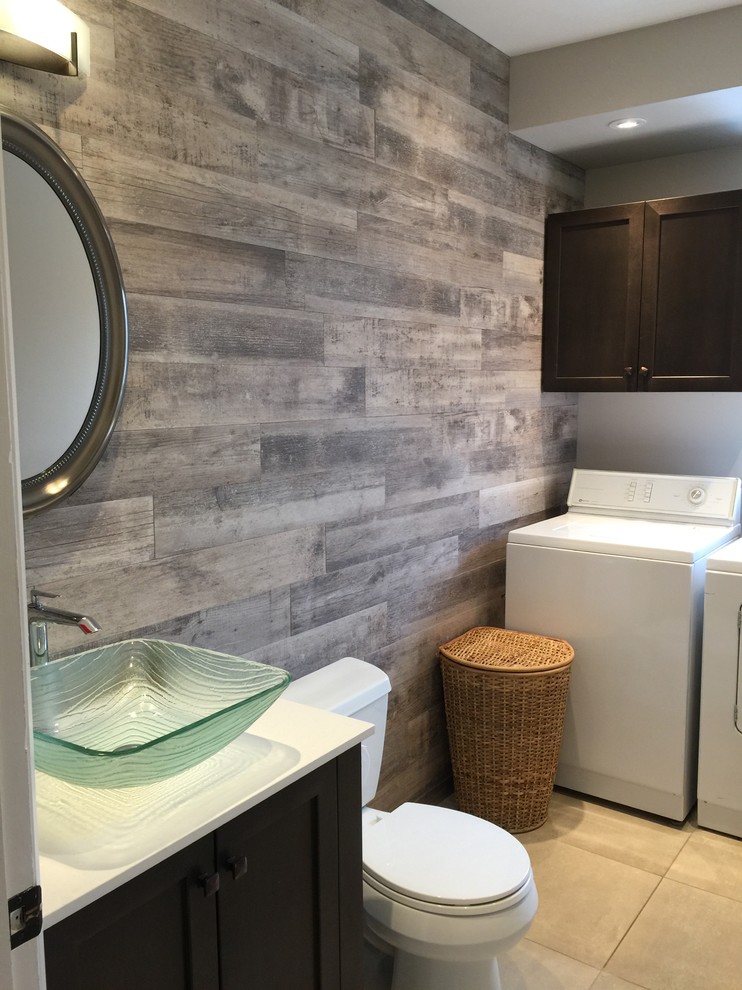 Inspiration for a mid-sized transitional single-wall utility room in Montreal with a single-bowl sink, shaker cabinets, dark wood cabinets, solid surface benchtops, grey walls, porcelain floors, a side-by-side washer and dryer, beige floor and white benchtop.
