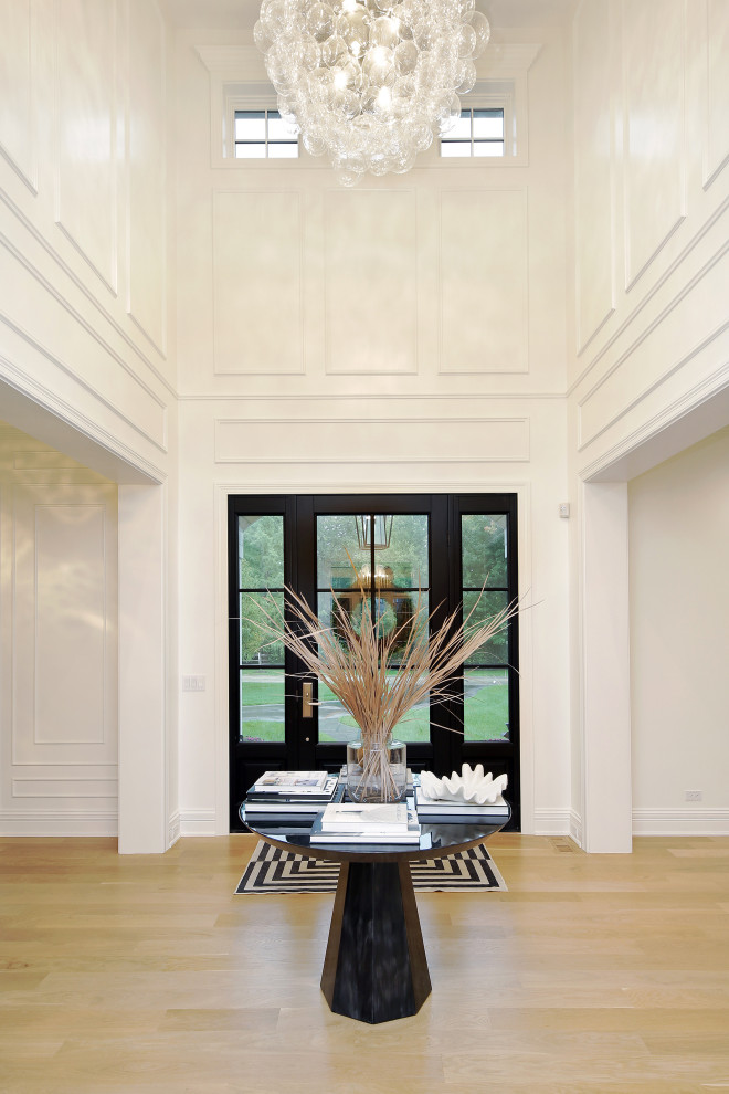 Large transitional light wood floor foyer photo in Chicago with white walls and a glass front door
