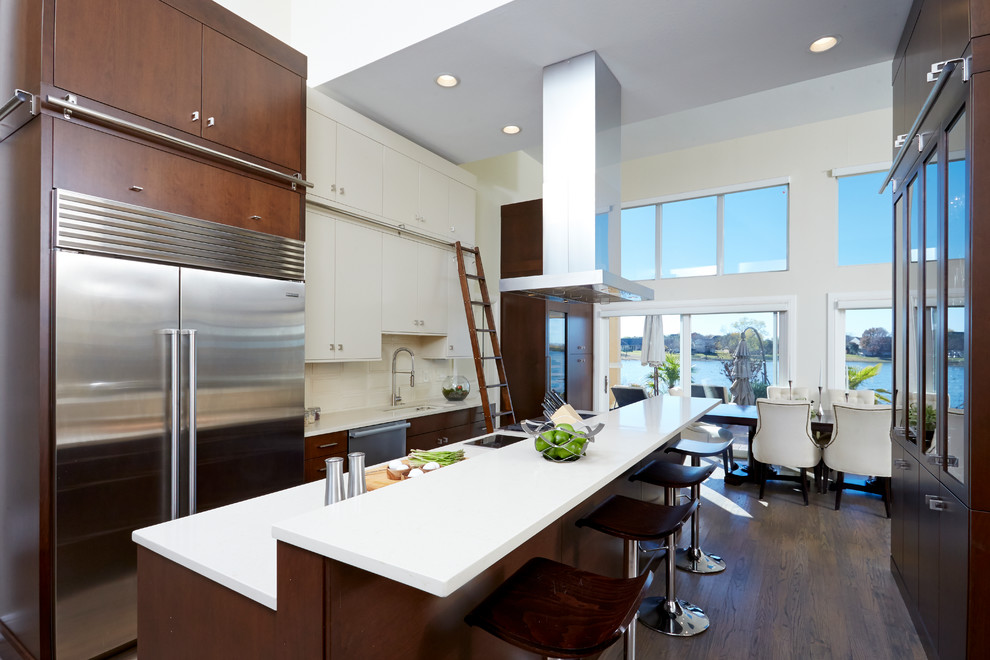 Inspiration for a contemporary eat-in kitchen in Dallas with an undermount sink, flat-panel cabinets, dark wood cabinets, beige splashback, stainless steel appliances, dark hardwood floors and with island.