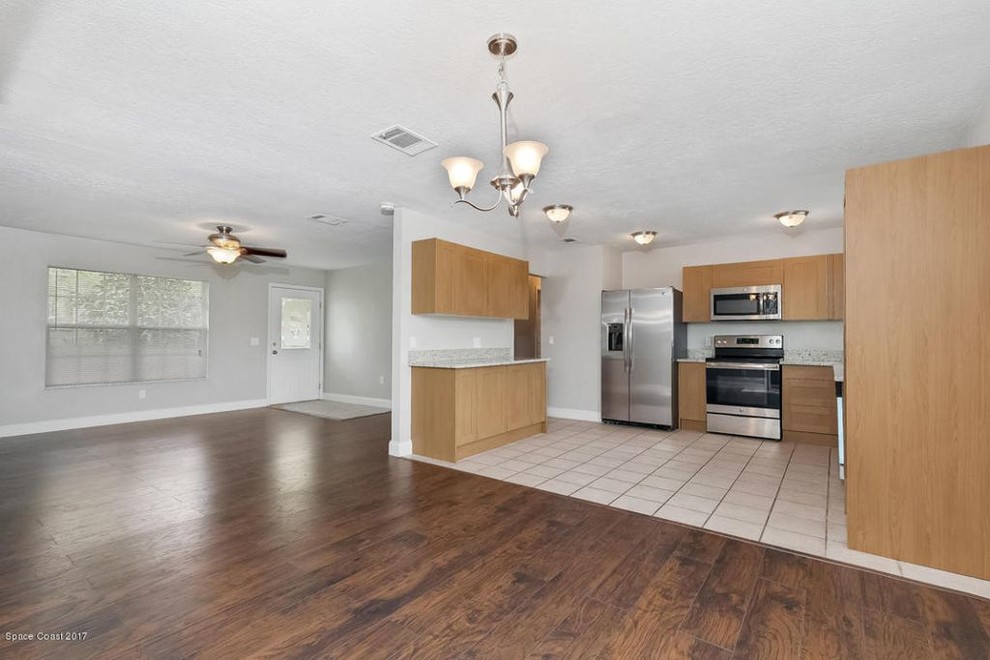 This is an example of a mid-sized traditional u-shaped open plan kitchen in Orlando with an undermount sink, shaker cabinets, light wood cabinets, granite benchtops, stainless steel appliances, ceramic floors, no island, beige floor and beige benchtop.
