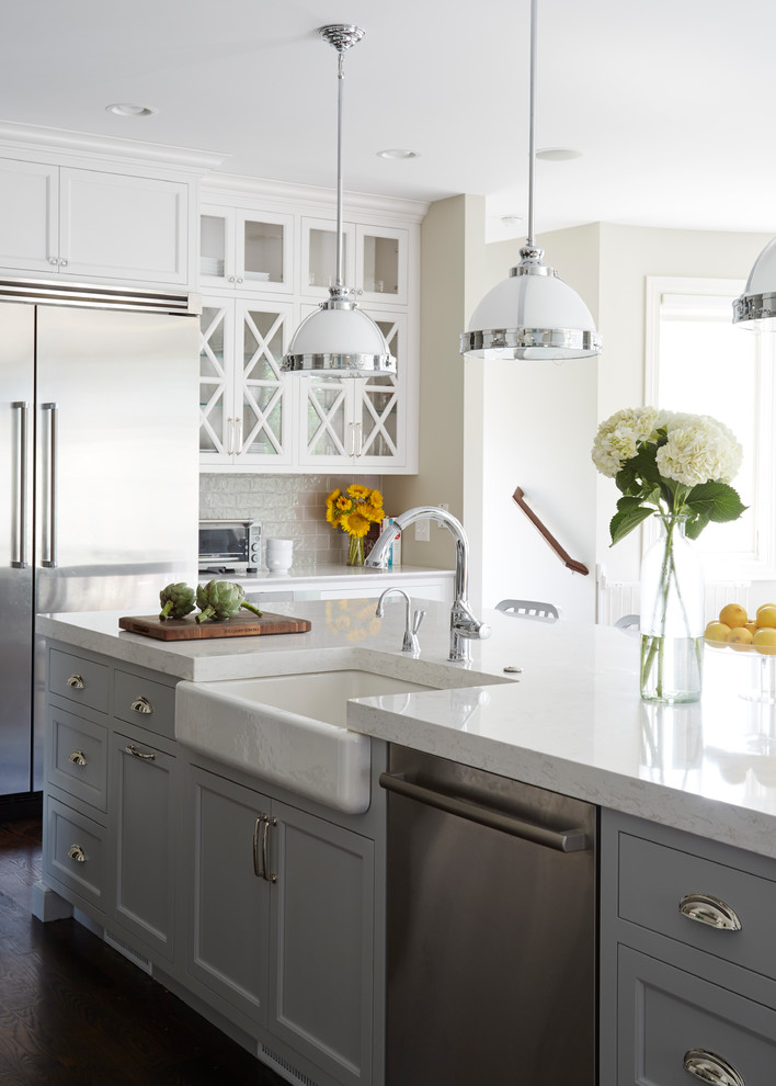 Inspiration for a traditional kitchen in Chicago with a farmhouse sink, shaker cabinets, grey cabinets, grey splashback, subway tile splashback, stainless steel appliances, dark hardwood floors and with island.