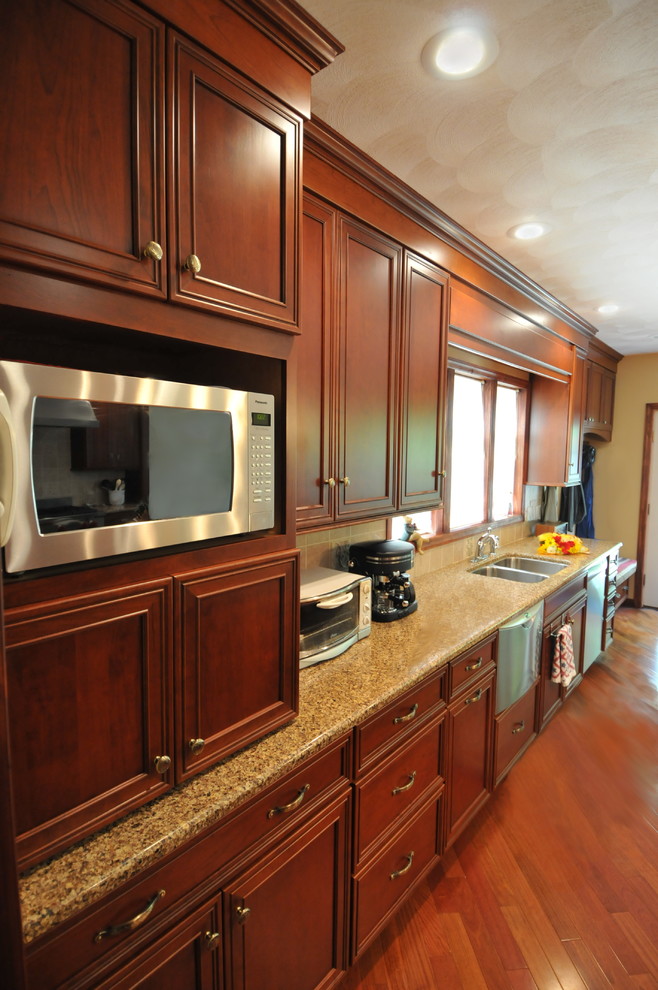Inspiration for a large transitional medium tone wood floor eat-in kitchen remodel in New York with an undermount sink, recessed-panel cabinets, dark wood cabinets, quartz countertops, beige backsplash, ceramic backsplash, stainless steel appliances and an island