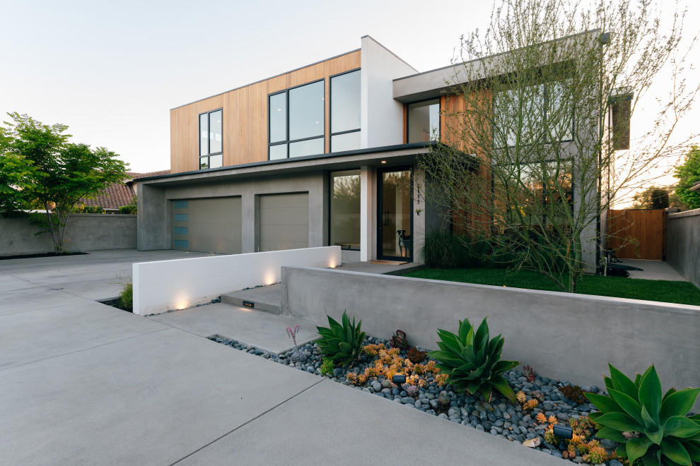 Cette photo montre une grande façade de maison grise moderne en bois à un étage avec un toit plat.