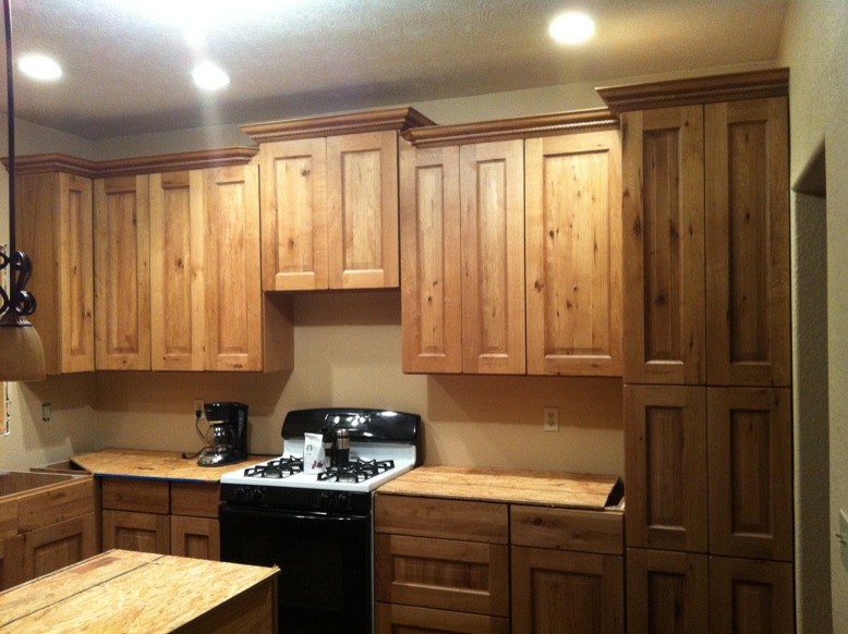 Example of a mid-sized mountain style l-shaped kitchen design with recessed-panel cabinets, distressed cabinets and laminate countertops