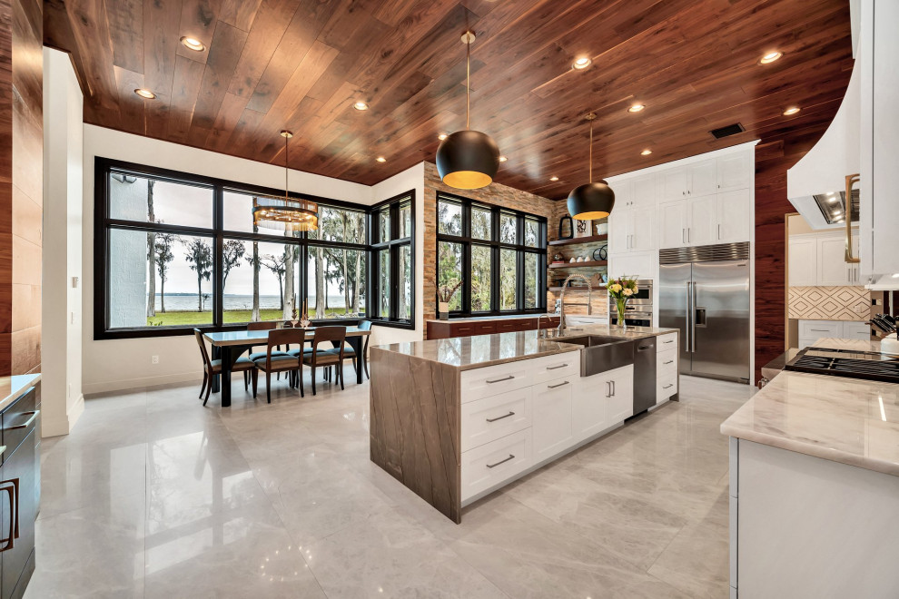 Example of a large transitional u-shaped wood ceiling eat-in kitchen design in Orlando with a farmhouse sink, shaker cabinets, white cabinets, stainless steel appliances and an island