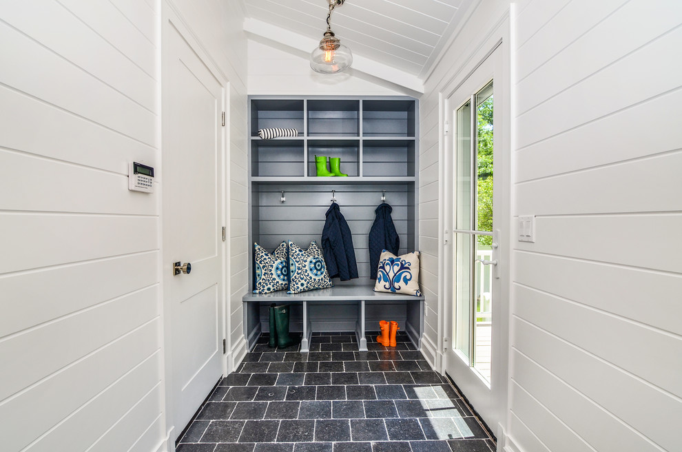 This is an example of a small transitional mudroom in New York with white walls and grey floor.