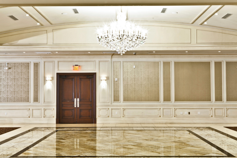 На фото: большой коридор в классическом стиле с белыми стенами, бежевым полом, кессонным потолком и панелями на части стены с