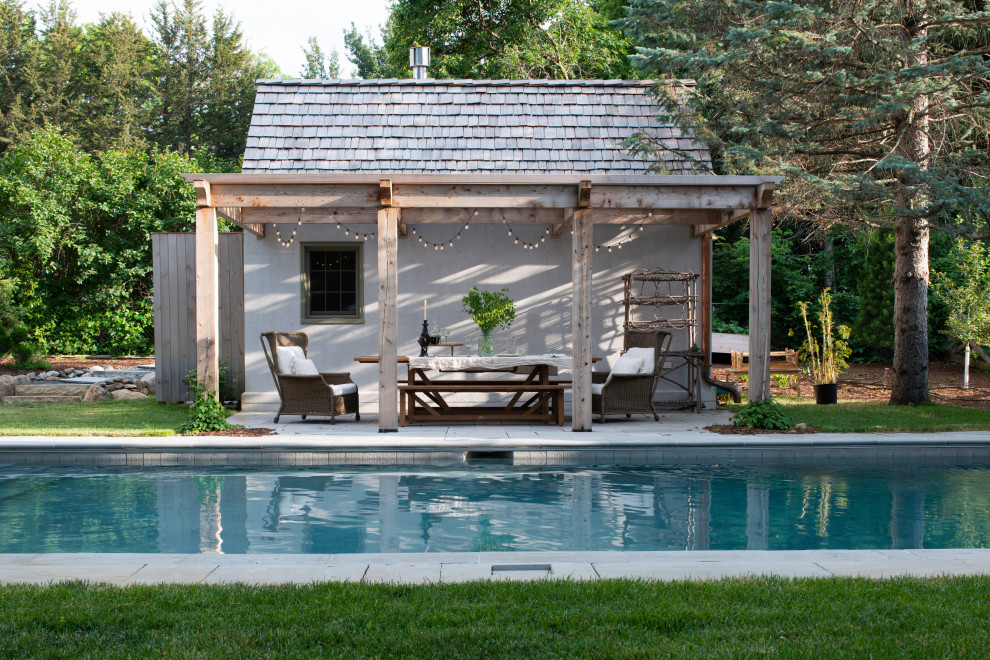Inspiration for a traditional back swimming pool in Minneapolis with a pool house and natural stone paving.