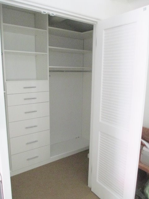 Small modern gender-neutral walk-in wardrobe in Los Angeles with flat-panel cabinets and white cabinets.