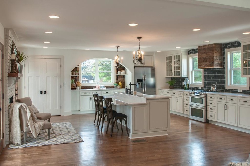 Photo of a large country single-wall eat-in kitchen in Nashville with a farmhouse sink, beaded inset cabinets, white cabinets, marble benchtops, grey splashback, cement tile splashback, stainless steel appliances, light hardwood floors, with island, brown floor and white benchtop.