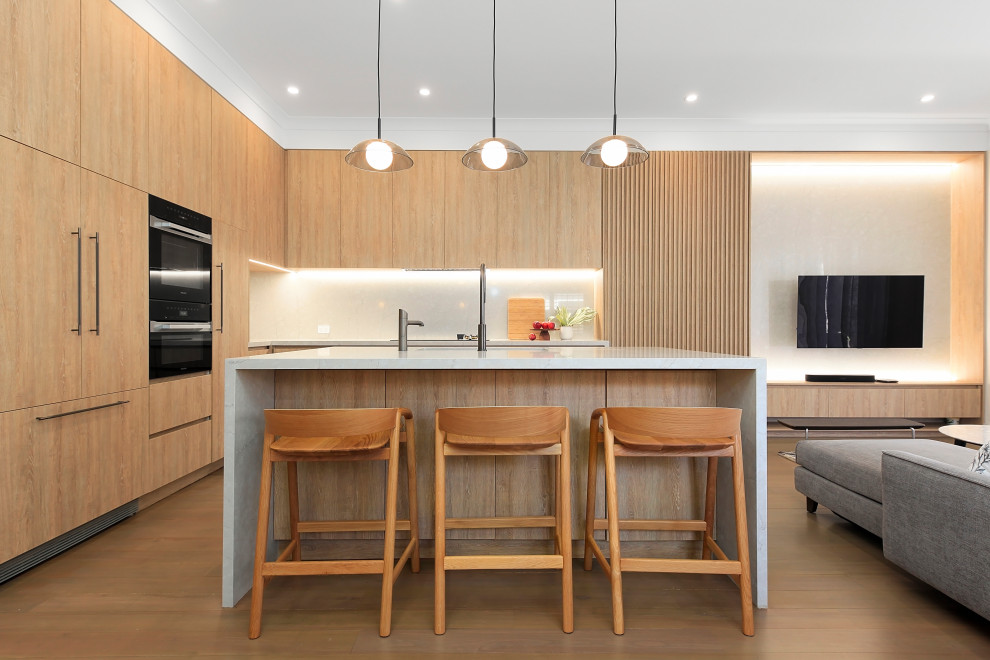 Inspiration for a small contemporary l-shaped light wood floor and brown floor open concept kitchen remodel in Sydney with a drop-in sink, flat-panel cabinets, light wood cabinets, quartz countertops, gray backsplash, stone slab backsplash, black appliances, an island and gray countertops