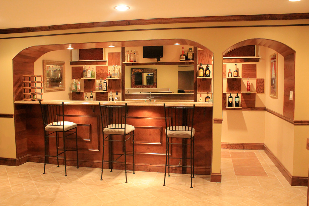 Mid-sized modern galley seated home bar in DC Metro with a drop-in sink, raised-panel cabinets, ceramic floors, medium wood cabinets, granite benchtops, brown splashback, timber splashback and beige floor.