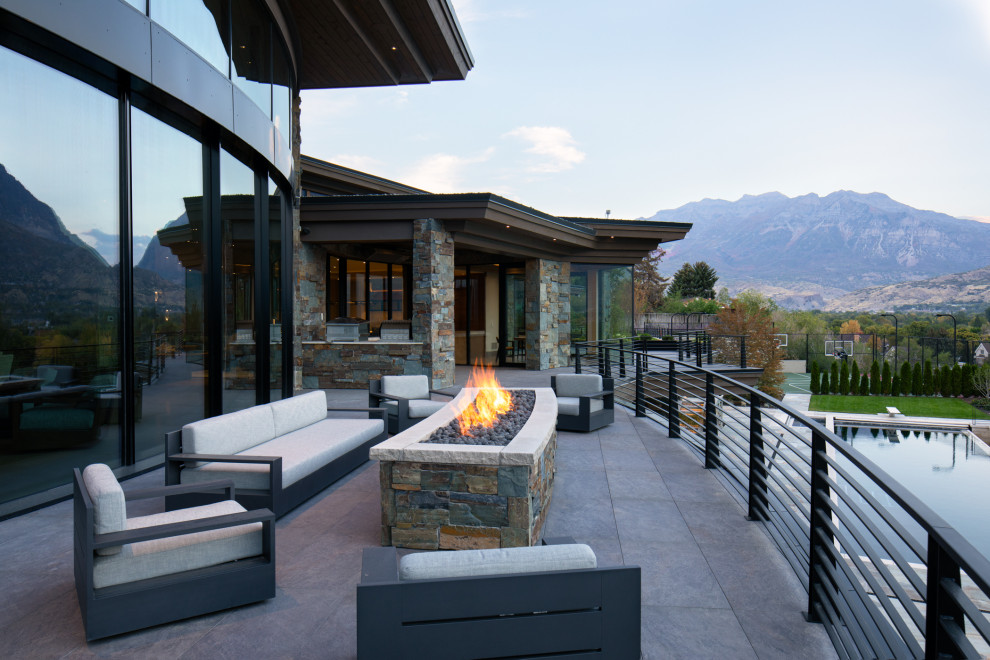 Large asian backyard and first floor deck in Salt Lake City with a fire feature, a roof extension and metal railing.
