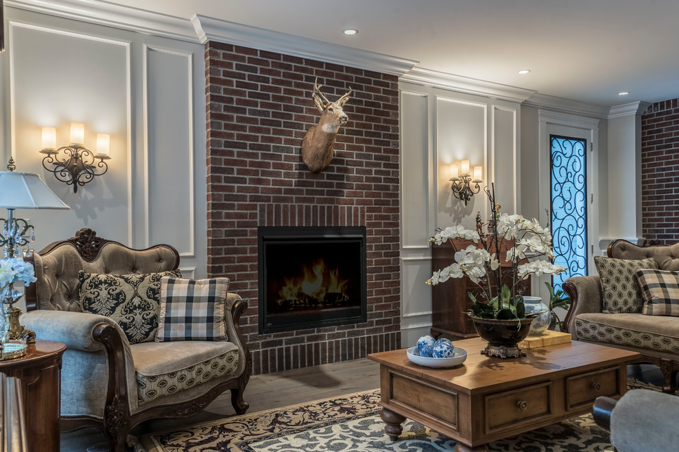Photo of a mid-sized traditional open concept family room in Vancouver with beige walls, medium hardwood floors, a standard fireplace, a brick fireplace surround, no tv and brown floor.