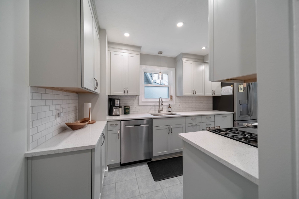 Small minimalist galley cement tile floor and gray floor enclosed kitchen photo in Cleveland with an undermount sink, shaker cabinets, gray cabinets, quartzite countertops, white backsplash, subway tile backsplash, stainless steel appliances, no island and white countertops