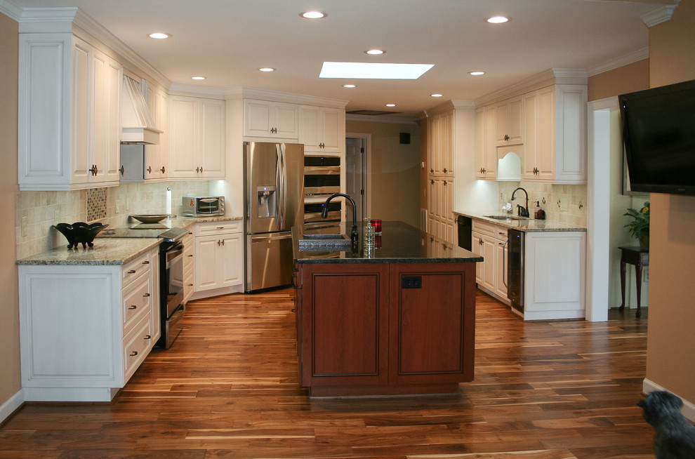 Large traditional open plan kitchen in Raleigh with an undermount sink, raised-panel cabinets, white cabinets, granite benchtops, beige splashback, terra-cotta splashback, stainless steel appliances, medium hardwood floors and with island.
