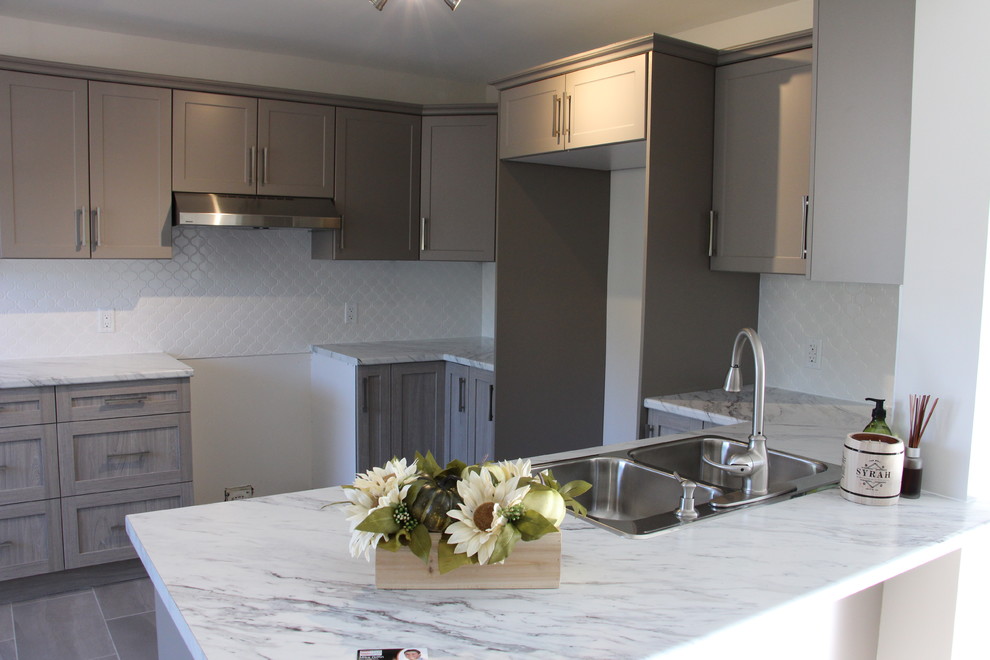 Mid-sized mountain style u-shaped porcelain tile eat-in kitchen photo in Toronto with a double-bowl sink, shaker cabinets, gray cabinets, laminate countertops, white backsplash, porcelain backsplash and a peninsula