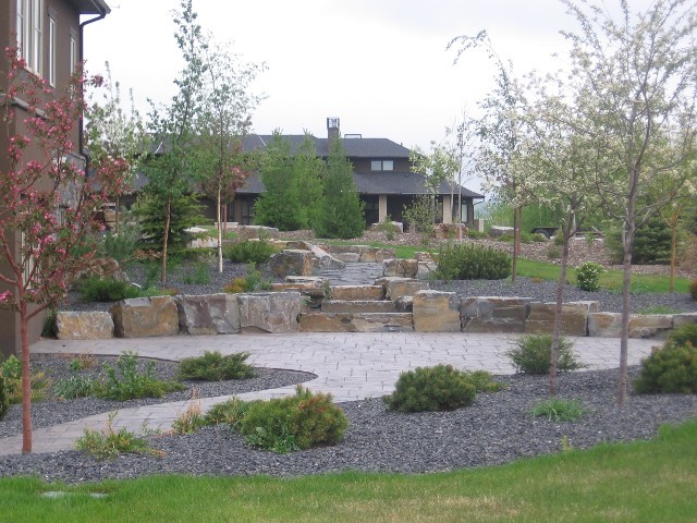 Inspiration for a mid-sized rustic partial sun backyard stone landscaping in Calgary.