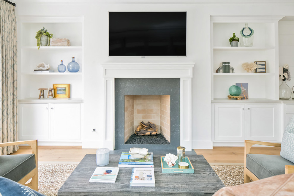 Inspiration for a mid-sized beach style open concept living room in Orange County with white walls, light hardwood floors, a standard fireplace and a wall-mounted tv.