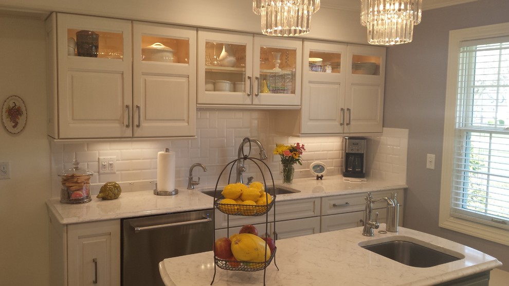 Small transitional u-shaped ceramic tile eat-in kitchen photo with a double-bowl sink, raised-panel cabinets, white cabinets, marble countertops, white backsplash, subway tile backsplash, stainless steel appliances and an island