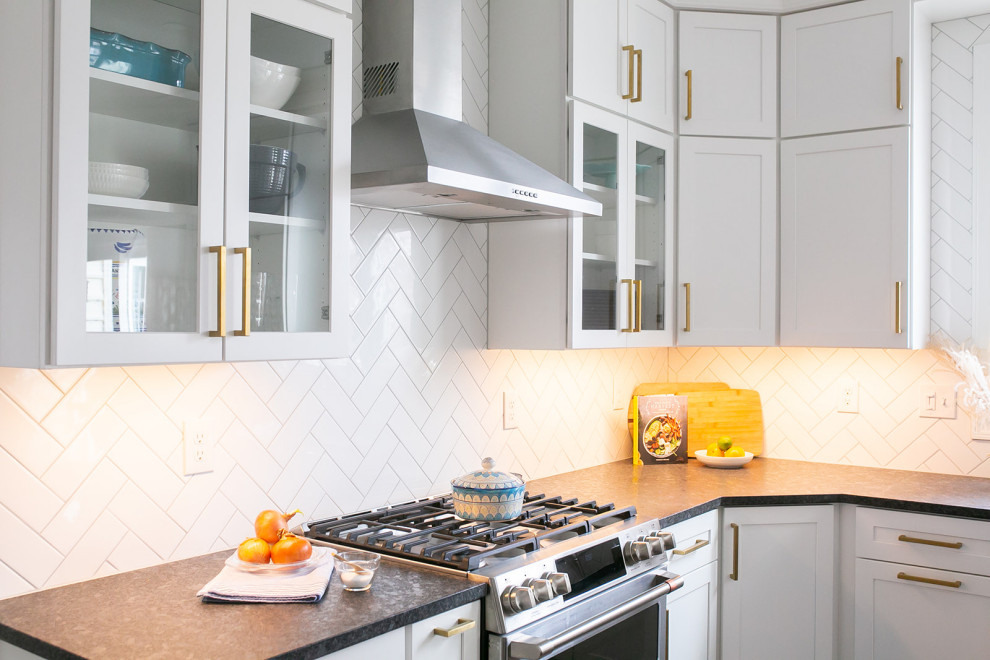 Large transitional l-shaped brown floor kitchen pantry photo in Baltimore with a drop-in sink, shaker cabinets, white cabinets, quartz countertops, white backsplash, ceramic backsplash, stainless steel appliances, an island and white countertops