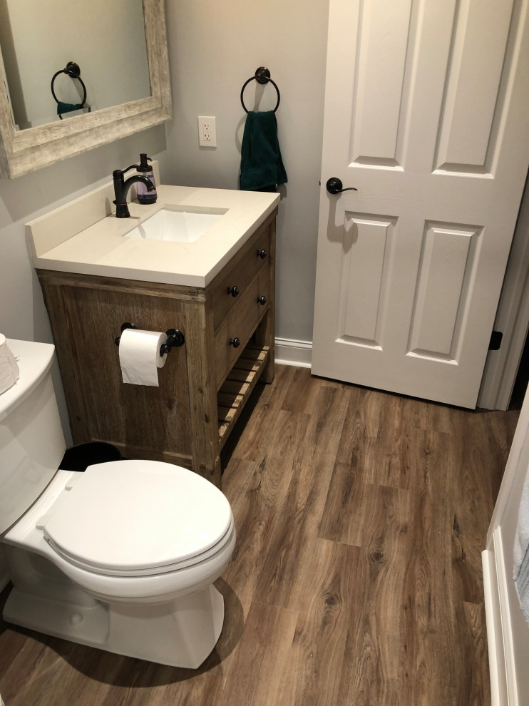 Design ideas for a large modern 3/4 bathroom in Philadelphia with shaker cabinets, light wood cabinets, an alcove shower, a one-piece toilet, white tile, grey walls, light hardwood floors, a console sink, solid surface benchtops, brown floor, a shower curtain and white benchtops.