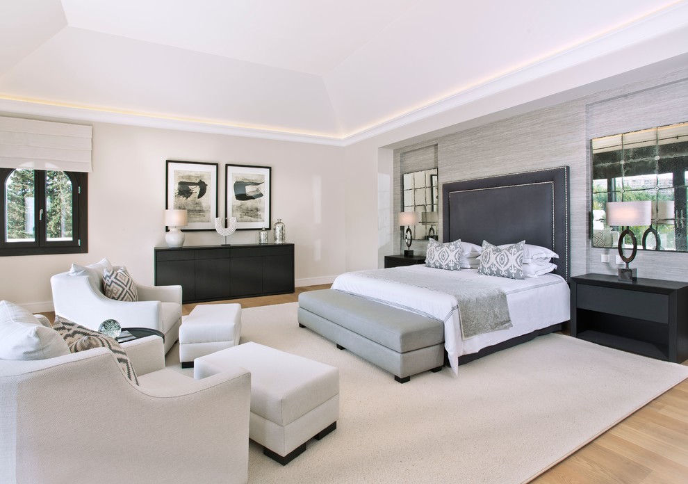 This is an example of an expansive contemporary master bedroom in Malaga with beige walls, medium hardwood floors, brown floor and a wood stove.