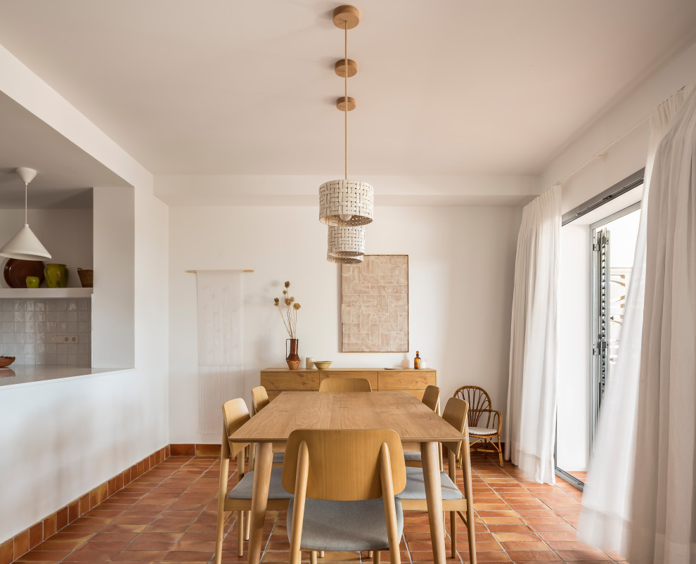 Photo of a small mediterranean kitchen/dining combo in Valencia with white walls, terra-cotta floors and brown floor.