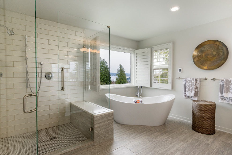 Inspiration for a large transitional master bathroom in Seattle with recessed-panel cabinets, grey cabinets, a freestanding tub, a double shower, a one-piece toilet, beige tile, glass tile, grey walls, porcelain floors, a vessel sink, engineered quartz benchtops, grey floor and a hinged shower door.