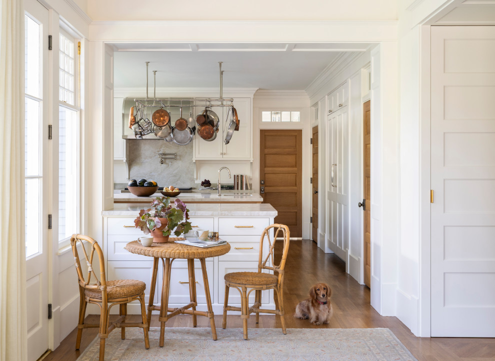 Inspiration for a timeless medium tone wood floor and brown floor eat-in kitchen remodel in Houston with a farmhouse sink, white cabinets, gray backsplash, marble backsplash, stainless steel appliances and an island