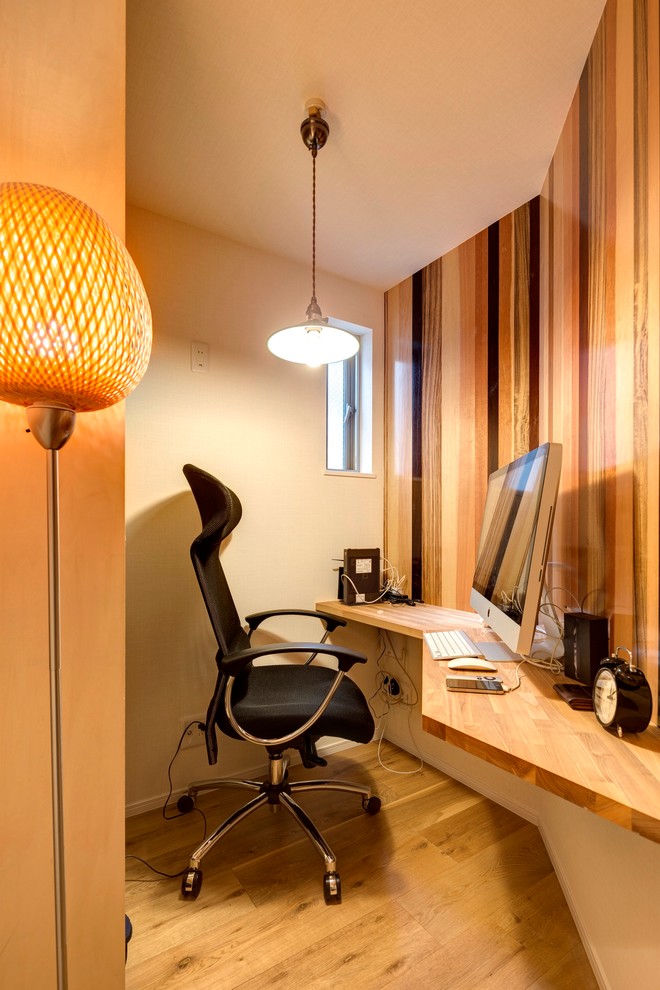 Photo of a small midcentury home office in Other with multi-coloured walls, medium hardwood floors, a built-in desk and brown floor.