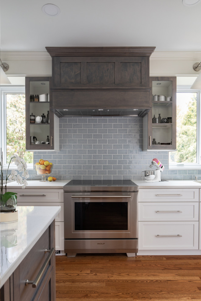 Enclosed kitchen - mid-sized transitional l-shaped medium tone wood floor and brown floor enclosed kitchen idea with an undermount sink, shaker cabinets, white cabinets, quartz countertops, blue backsplash, subway tile backsplash, stainless steel appliances, an island and white countertops