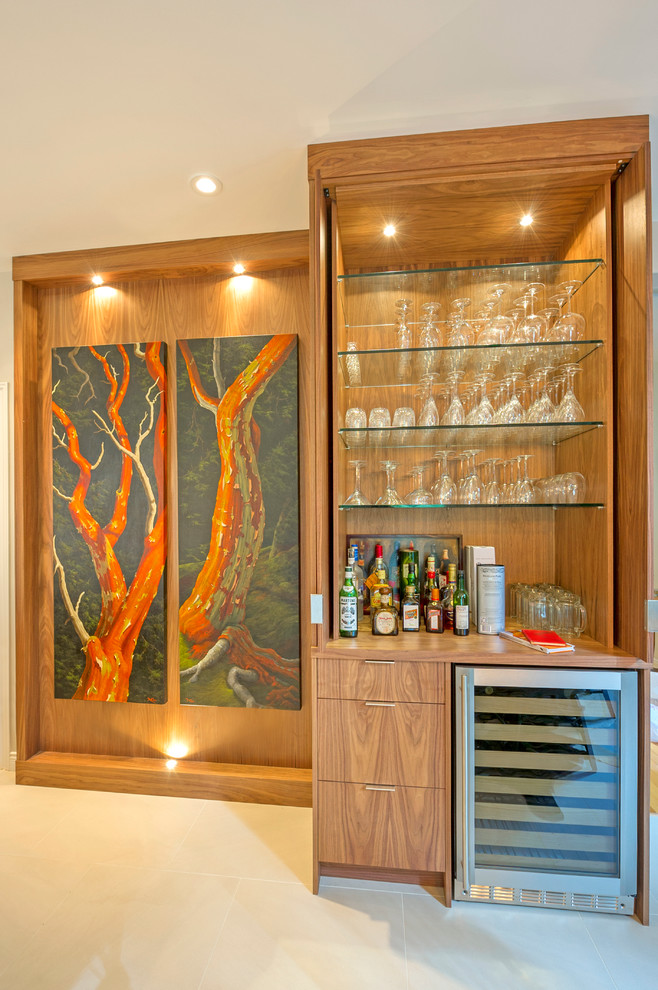 This is an example of a large contemporary l-shaped home bar in Vancouver with flat-panel cabinets, medium wood cabinets, quartzite benchtops, beige splashback, stone slab splashback and ceramic floors.