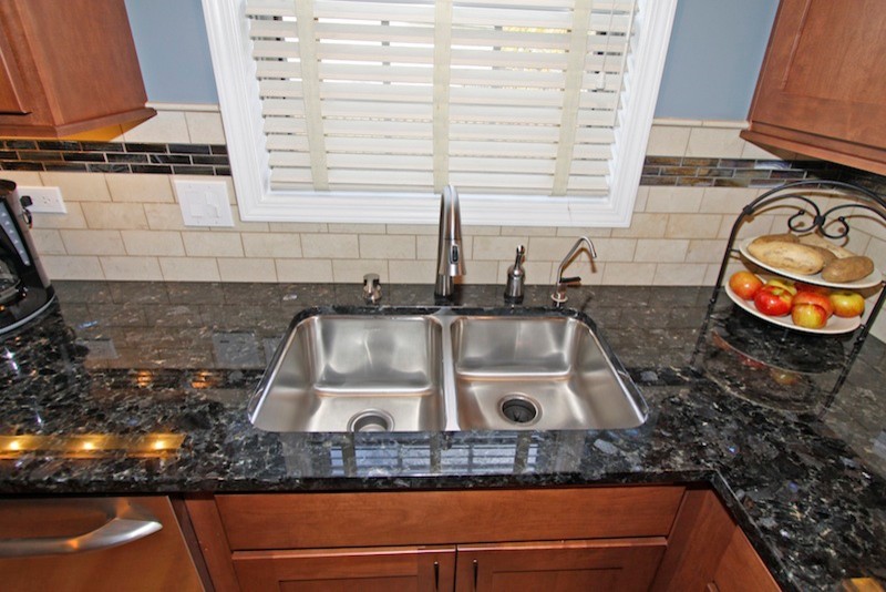 Eat-in kitchen - mid-sized transitional u-shaped light wood floor eat-in kitchen idea in Chicago with an undermount sink, recessed-panel cabinets, medium tone wood cabinets, granite countertops, beige backsplash, stone tile backsplash, stainless steel appliances and no island