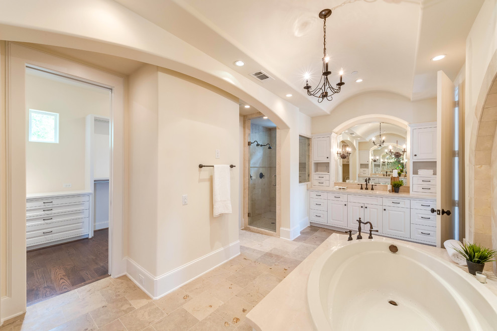 Large mediterranean master bathroom in Houston with an undermount sink, shaker cabinets, white cabinets, marble benchtops, a drop-in tub, a corner shower, a one-piece toilet, brown tile, stone tile, yellow walls and marble floors.