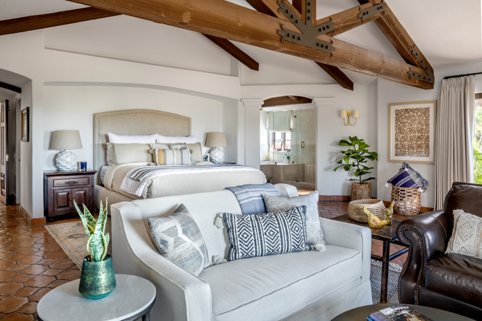 Großes Mediterranes Gästezimmer mit weißer Wandfarbe, braunem Holzboden, Eckkamin, verputzter Kaminumrandung, braunem Boden und freigelegten Dachbalken in Orange County