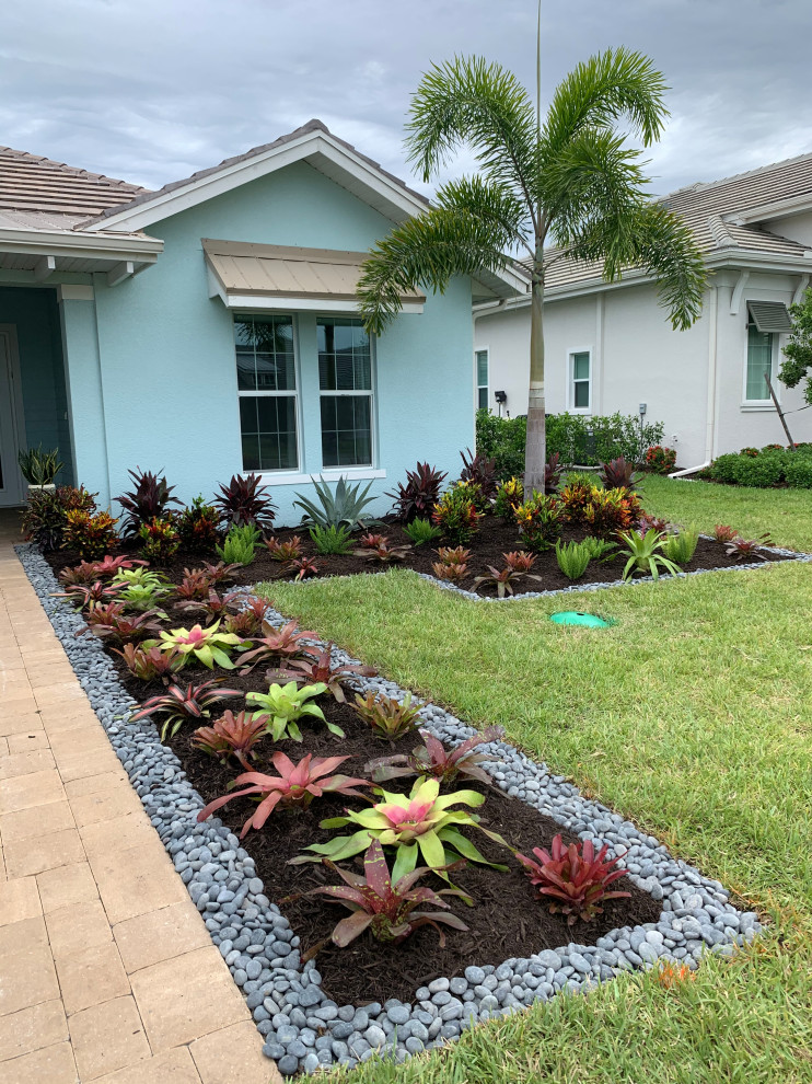 Photo of a mid-sized tropical front yard full sun formal garden in Miami with with rock feature and river rock.
