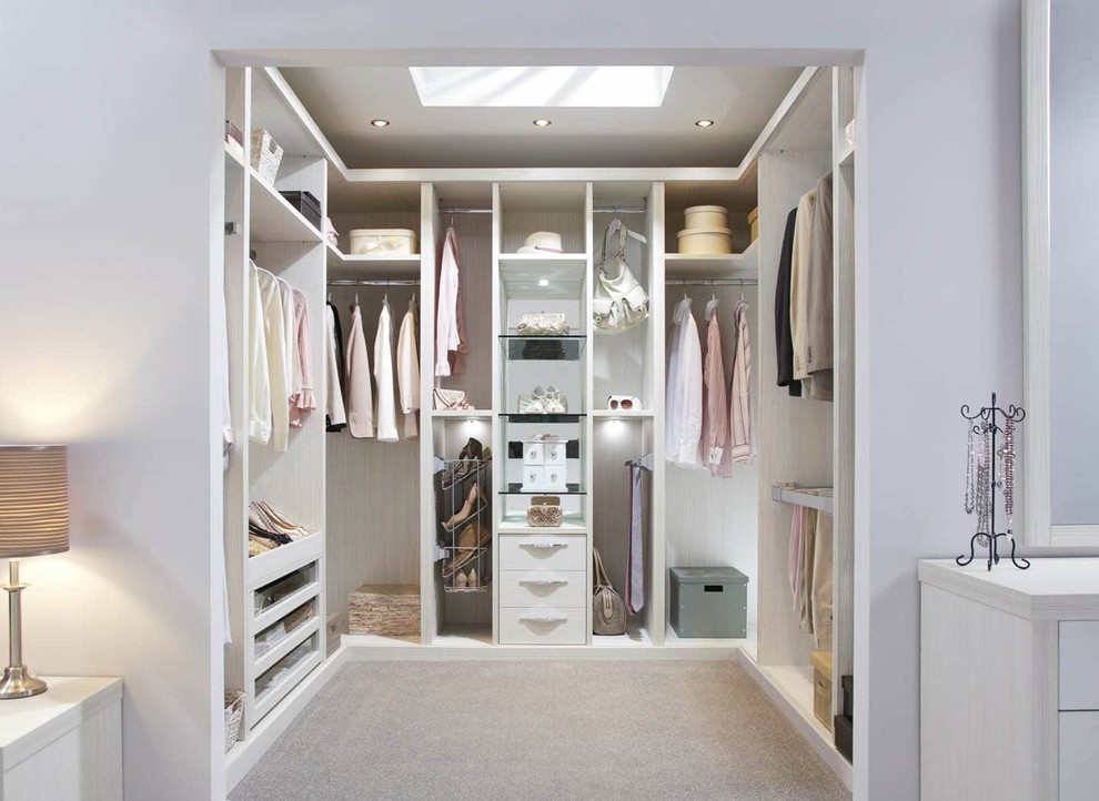This is an example of a mid-sized contemporary gender-neutral walk-in wardrobe in London with open cabinets, light wood cabinets, carpet and beige floor.