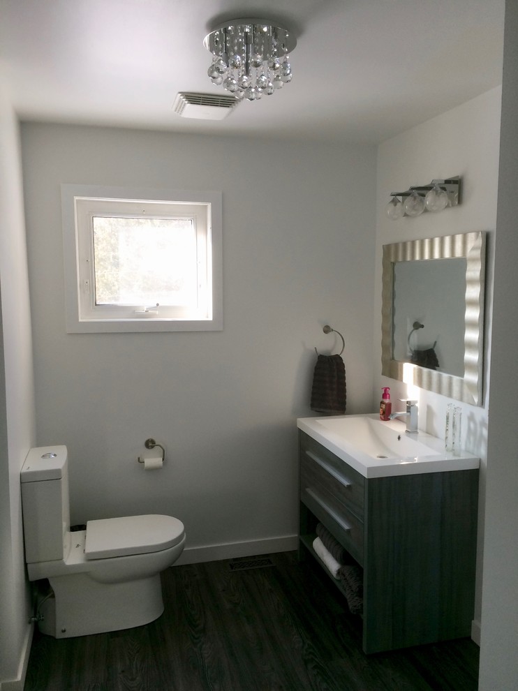 Example of a mid-sized transitional master linoleum floor and gray floor alcove shower design with flat-panel cabinets, gray cabinets, a two-piece toilet, white walls, an integrated sink and solid surface countertops