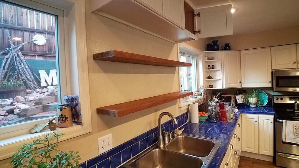 Large mountain style l-shaped light wood floor and brown floor eat-in kitchen photo in Denver with a double-bowl sink, raised-panel cabinets, white cabinets, tile countertops, blue backsplash, ceramic backsplash, stainless steel appliances and an island
