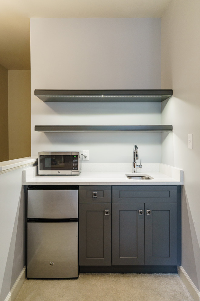 Photo of a small contemporary single-wall wet bar in Raleigh with an undermount sink, shaker cabinets, grey cabinets, quartzite benchtops, white splashback, stone slab splashback and carpet.