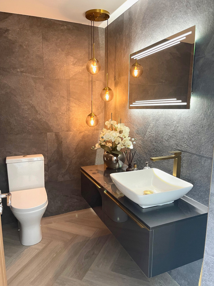 Idée de décoration pour un petit WC et toilettes design avec des portes de placard noires, des carreaux de porcelaine et meuble-lavabo suspendu.