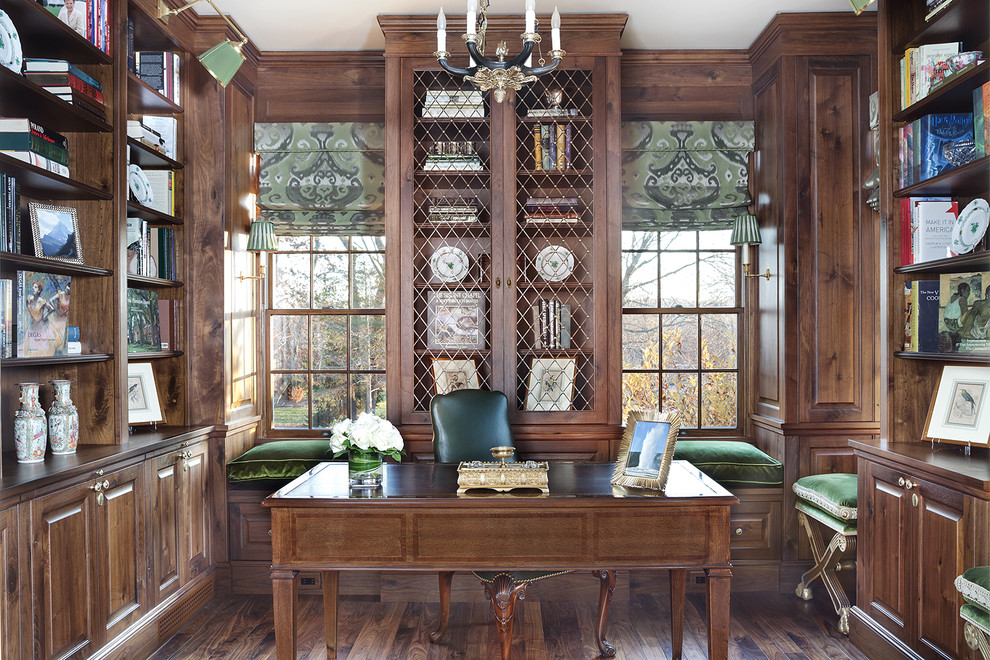 Design ideas for a mid-sized traditional home office in New York with a library, dark hardwood floors, a freestanding desk, brown walls, no fireplace and brown floor.