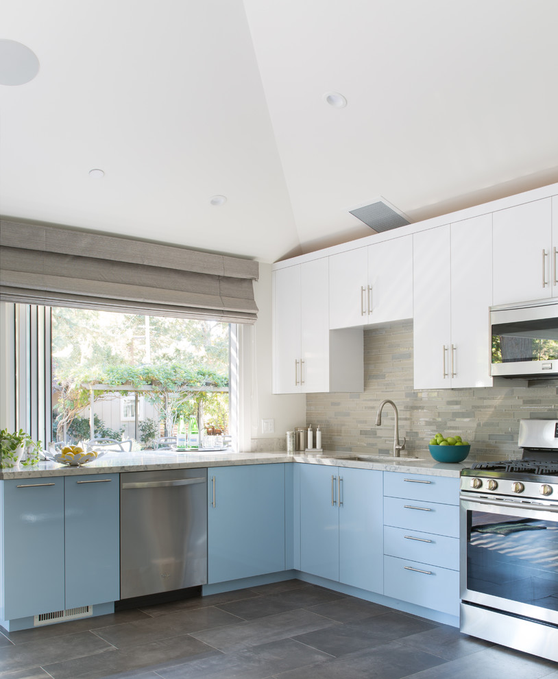 Design ideas for a mid-sized transitional l-shaped open plan kitchen in San Francisco with an undermount sink, flat-panel cabinets, blue cabinets, quartzite benchtops, beige splashback, glass tile splashback, stainless steel appliances, porcelain floors, no island and grey floor.