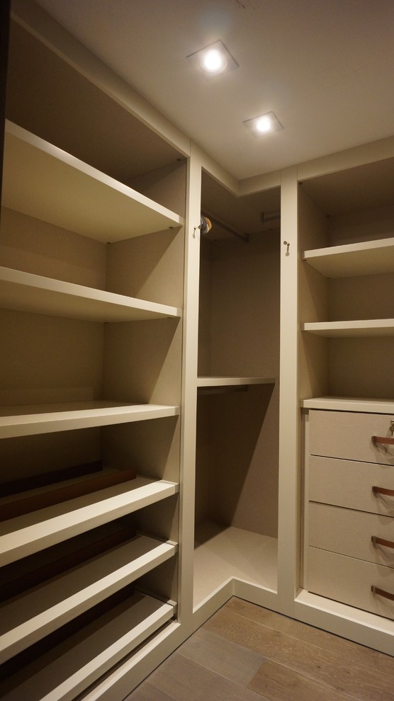 Photo of a mid-sized contemporary men's dressing room in Miami with flat-panel cabinets, light wood cabinets and light hardwood floors.