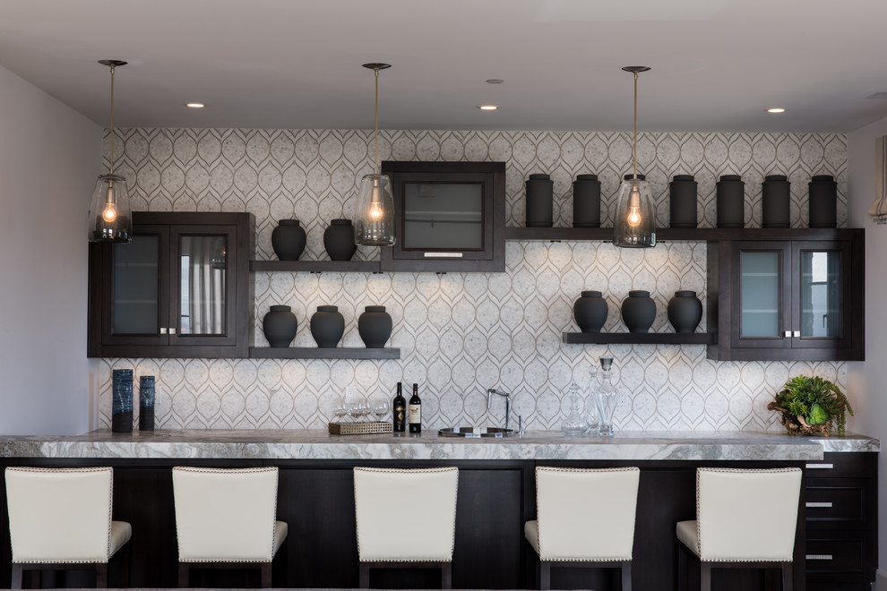 Mid-sized modern galley seated home bar in Orange County with dark wood cabinets, granite benchtops, white splashback, mosaic tile splashback and glass-front cabinets.