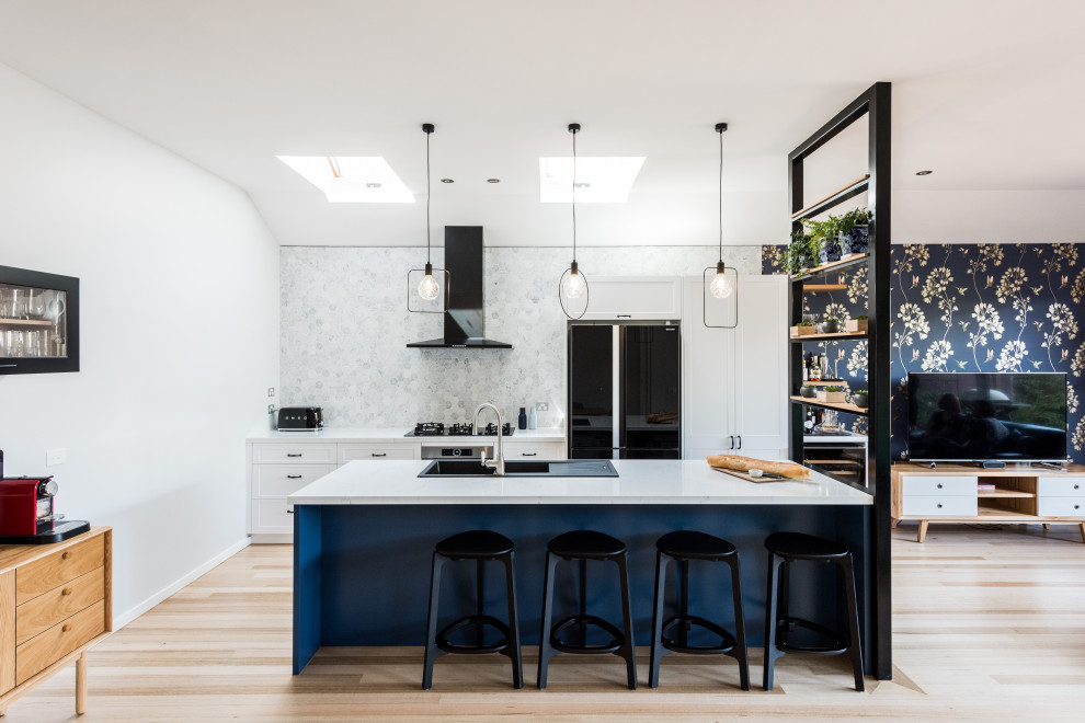 Photo of a mid-sized transitional galley kitchen in Melbourne with a drop-in sink, shaker cabinets, white cabinets, grey splashback, with island, beige floor and white benchtop.